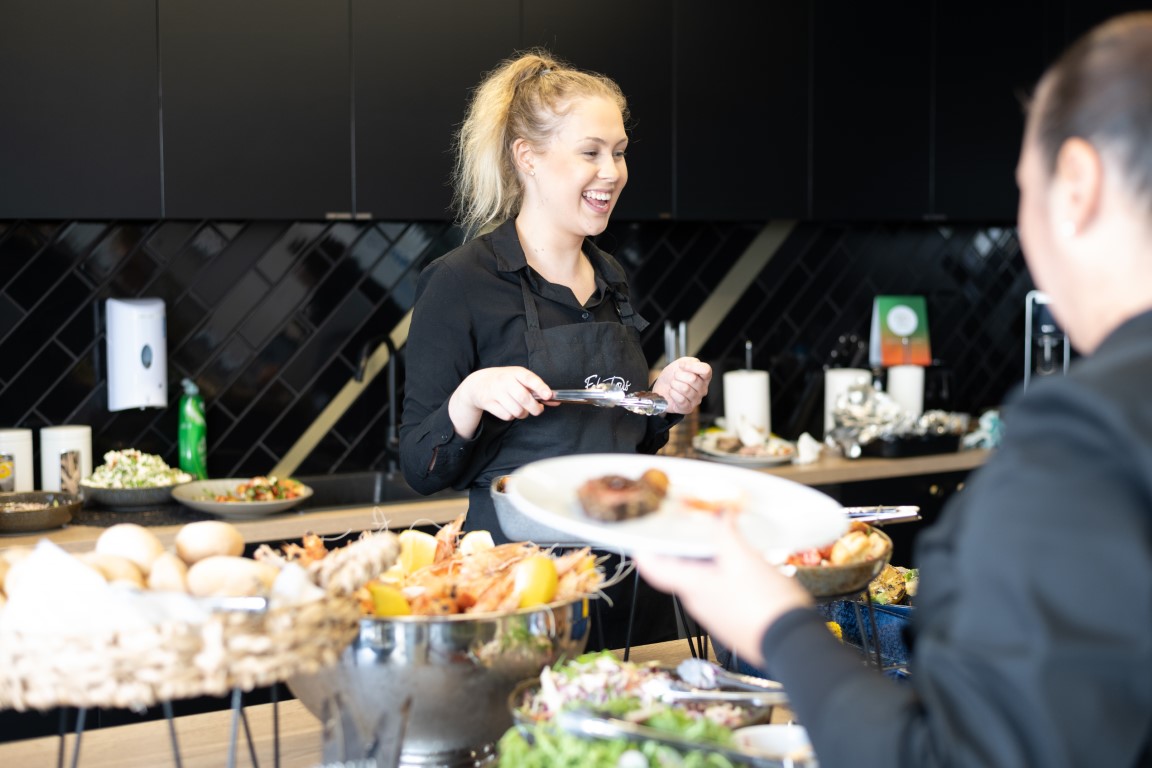 Catering staff member serving guests at a buffet
